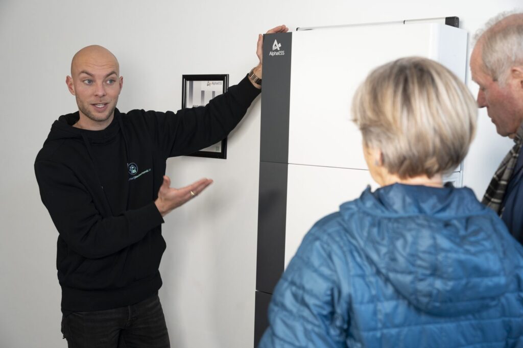 Een adviseur legt bezoekers een AlphaESS-thuisbatterij uit