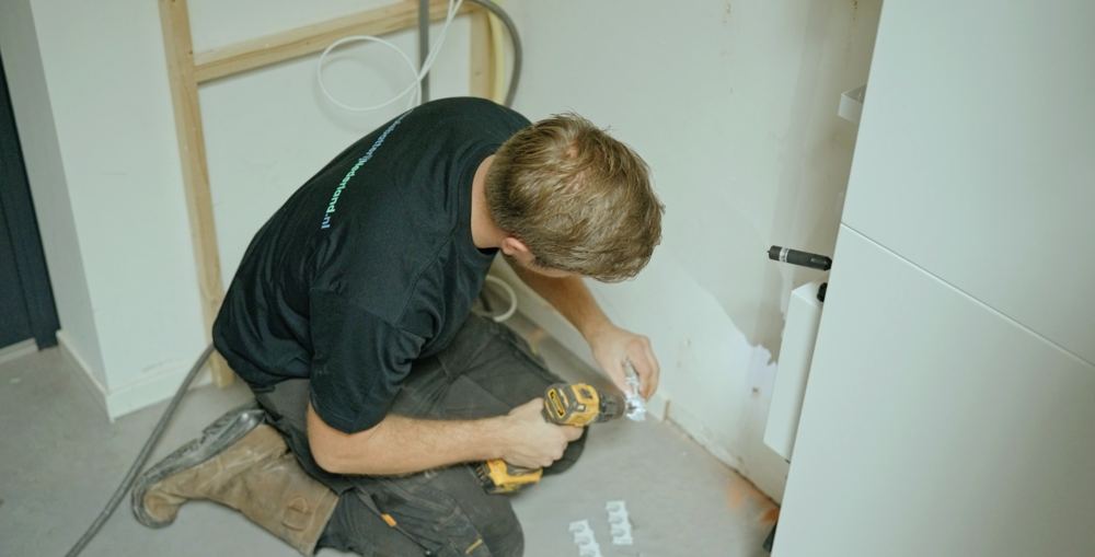 Monteur boort de muurbeugel voor een thuisbatterij vast