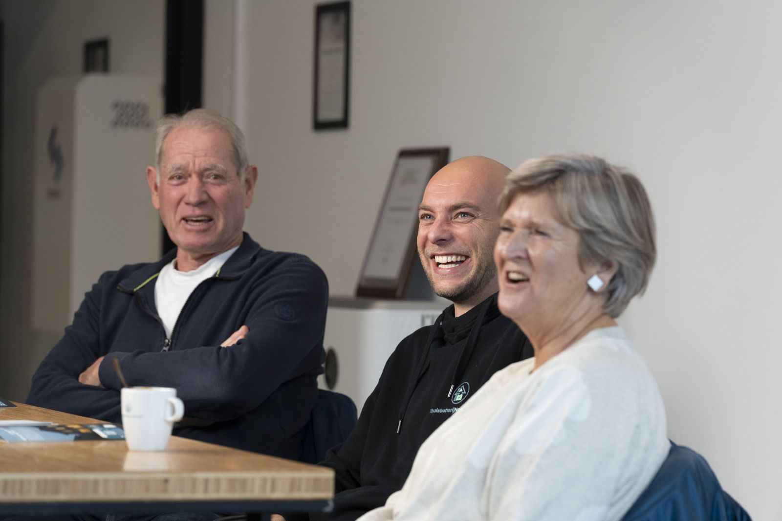 Tevreden klanten lachen samen met de adviseur aan tafel in de showroom